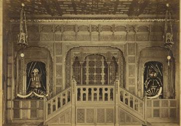 black and white photo of a carved hall with horns and armour on display