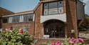 Exterior of The Stables Theatre, Hastings, a brick-built arts venue framed by colourful flower beds.