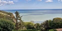 Sea views from Rocklands Holiday Park overlooking coastal cliffs, trees and the English Channel.