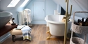 Loft-style bathroom at The Laindons with freestanding bath, skylights and wooden flooring.