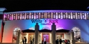 White Rock Theatre exterior lit at night with colourful lights and visitors gathered outside entrance.