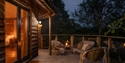Treehouse balcony at Downash Wood with outdoor seating overlooking the forest at dusk.