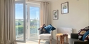 Bright and modern holiday cottage lounge with open balcony doors and countryside views near Rye.