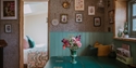 Boutique-style cabin interior with floral décor, dining table, and views into a cosy bedroom.
