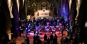 Singers of Hastings Philharmonic Orchestra on stage under coloured lights.