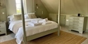 Spacious king bedroom at Judins Cottage, Burwash, with four-poster bed, soft furnishings and countryside views.