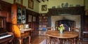 Historic dining room at Bateman’s featuring a large fireplace, bookshelves and antique furniture