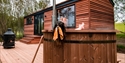 Wooden cabin on decking with a hot tub in the foreground.