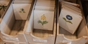 Hand-painted floral Rye Pottery tiles displayed in wooden storage trays.