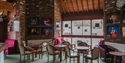 Seating area inside The Stables Theatre, Hastings, with café tables, brick walls and theatre photography displays.