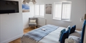 Modern ensuite bedroom at The Regent, Rye, featuring a king-size bed, armchair and wall-mounted TV.