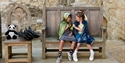 Children in medieval costumes seated on a wooden throne during a family activity at Bodiam Castle.