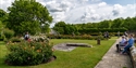 Visitors exploring the gardens at Herstmonceux Castle estate surrounded by colourful flowers and lawns.