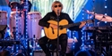 Guitarist performing live on stage with band and blue lighting at Rye Jazz Festival.