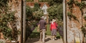 Visitors walking through a walled garden at Pashley Manor Gardens surrounded by colourful blooms.