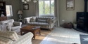 Bright living room at Judins Cottage, Burwash, featuring comfortable seating, wood burner and large windows.
