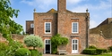 Rear view of Lamb House in Rye, with Georgian brickwork, lawn and landscaped garden borders.