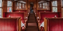 Vintage passenger carriage on the Kent & East Sussex Railway with red upholstered compartment seating.