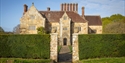 Bateman’s, Rudyard Kipling’s former home, viewed through a wrought-iron gate and clipped hedges.