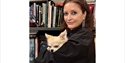 Tadhg Mae Projects founder holding a small dog in front of bookshelves at the Hastings gallery and bookshop.