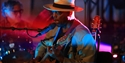 Live jazz performer singing and playing guitar under colourful stage lighting at Rye Jazz Festival.