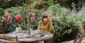 Visitor enjoying tea among colourful flower borders at Pashley Manor Gardens.