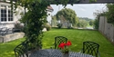 Judins Cottage garden in Burwash with patio seating, lawn and rolling countryside views beyond.