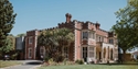 Exterior of Hastings Museum & Art Gallery, red-brick building with arched entrance and gardens.