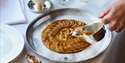 Apple tart being served at The Gallivant restaurant, with ice cream and glasses of wine.