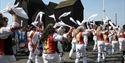 Traditional dancers waving white handkerchiefs during the Hastings Jack in the Green procession near the fishing huts.