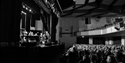 Audience seated inside White Rock Theatre watching live performance on stage in a large auditorium.