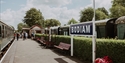 Bodiam station platform on the Kent & East Sussex Railway with heritage coaches and station signs.