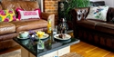 Cosy café lounge at Merriments, featuring leather sofas, homemade cakes and botanical décor.