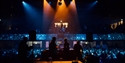 DJ performance at White Rock Theatre with crowd and balcony audience under blue and orange lighting.