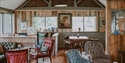 Cosy café space at Michelham Priory featuring colourful armchairs, wooden tables and garden views.