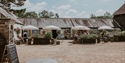 Michelham Priory courtyard café with outdoor seating, historic buildings and flower-filled planters.