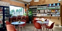 View of a cafe area with red plastic seats and shelves of produce in background.