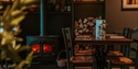 cosy pub interior with table and chairs next to a log burning stove.