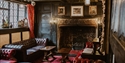 Historic lounge at The Mermaid Inn in Rye with leather chairs, wood panelling, and a large ornate fireplace.