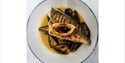 Seared fish fillet served over mussels in a creamy broth, presented in a white bowl with blue trim.