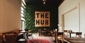 Interior of The Hub at Quarry Farm near Bodiam, featuring rustic wooden tables and a green wall with large 'The Hub' sign.