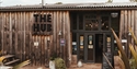 Exterior of The Hub at Quarry Farm near Bodiam, with wooden cladding, entrance doors, signs and an outdoor seating area.