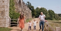 Family walking hand-in-hand along a path at Battle Abbey on a sunny day.