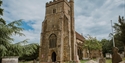 St Mary’s Church, Battle, with medieval stone tower, churchyard monuments and dramatic cloudy skies.