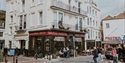 Exterior of The Albion pub on a Hastings street corner, with people sitting outside and nearby shops.