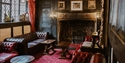 Historic lounge at The Mermaid Inn with Tudor wood panelling, leather seating and an ornate fireplace.