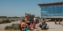 Group learning outdoors at Rye Harbour Discovery Centre, with guide leading activities beside modern glass building.