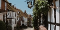 Mermaid Inn sign hanging above Mermaid Street in Rye, lined with historic timber-framed buildings.