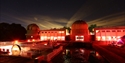 The Observatory Science Centre at night, illuminated in red with telescope domes under a starry sky.