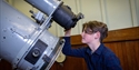 Child looks through a historic telescope inside an observatory dome at The Observatory Science Centre